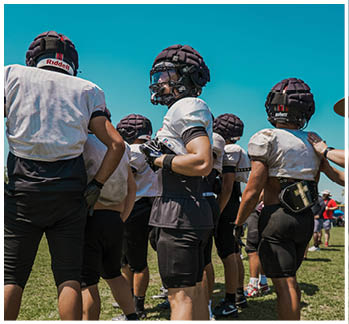 A football game is taking place with a group of men on the field. Description generated by AI
