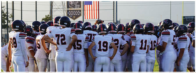 A football game is taking place on a field with players wearing blue and white uniforms. Description generated by AI