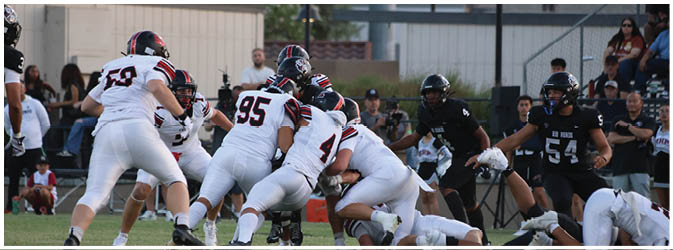 A football game is taking place on a field with players wearing blue and white uniforms. Description generated by AI