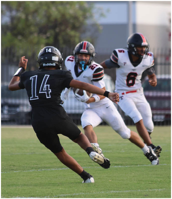Three football players in blue and white uniforms running on a field. Description generated by AI