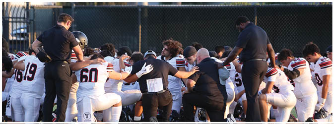 A football game is taking place on a field with players wearing blue and white uniforms. Description generated by AI