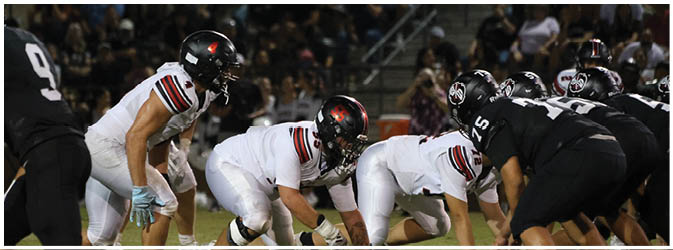 A football game is taking place on a field with players wearing blue and white uniforms. Description generated by AI