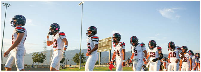 A football game is taking place on a field with players wearing blue and white uniforms. Description generated by AI