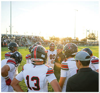 A football game is taking place with a group of men on the field. Description generated by AI