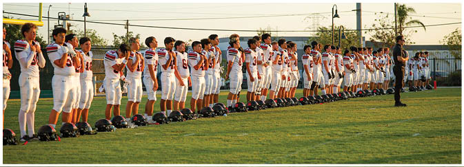 A football game is taking place on a field with players wearing blue and white uniforms. Description generated by AI