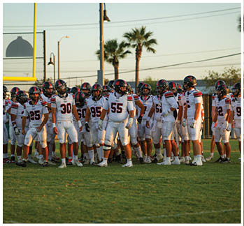 A football game is taking place with a group of men on the field. Description generated by AI