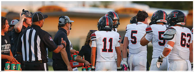 A football game is taking place on a field with players wearing blue and white uniforms. Description generated by AI