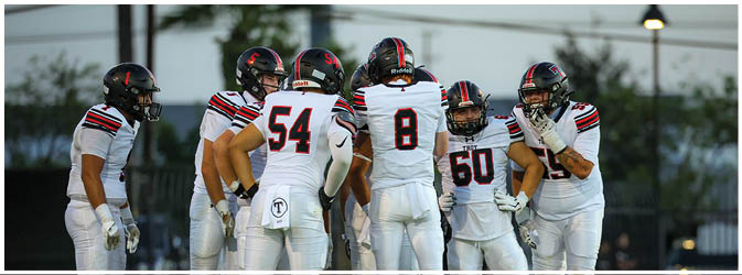 A football game is taking place on a field with players wearing blue and white uniforms. Description generated by AI