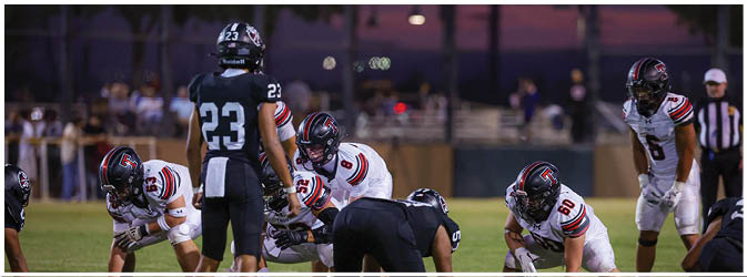 A football game is taking place on a field with players wearing blue and white uniforms. Description generated by AI