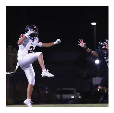 A football player in a white jersey with the number 85 on it is trying to catch a football. AI generated content