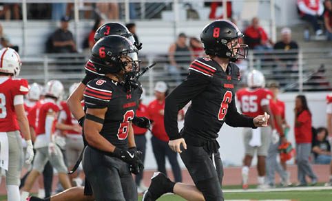 Two men wearing football uniforms are hugging each other on a field. AI generated content