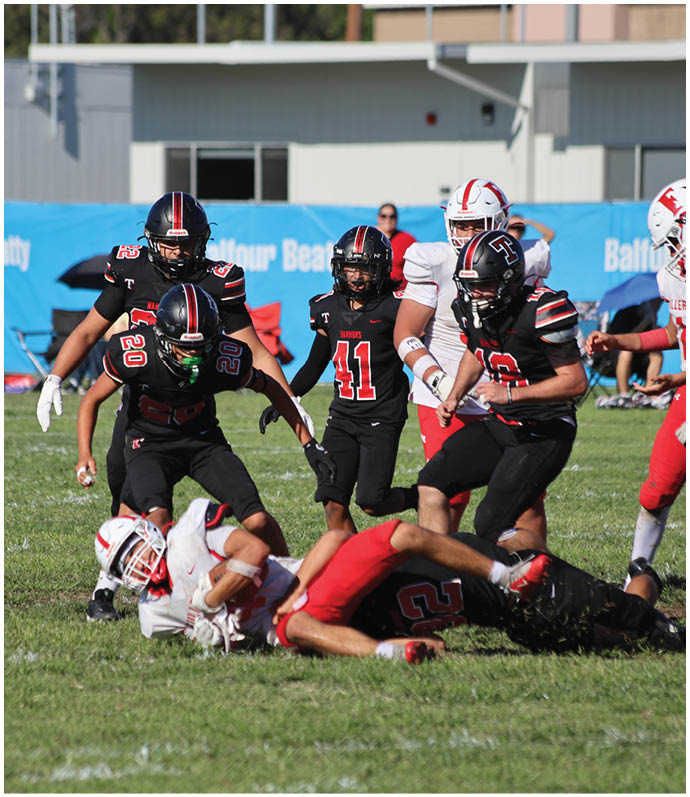 Three football players in blue and white uniforms running on a field. Description generated by AI