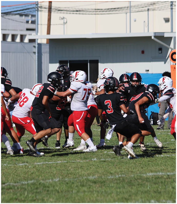 Three football players in blue and white uniforms running on a field. Description generated by AI