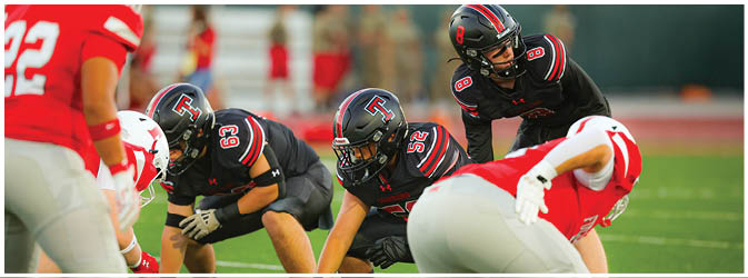 A football game is taking place on a field with players wearing blue and white uniforms. Description generated by AI