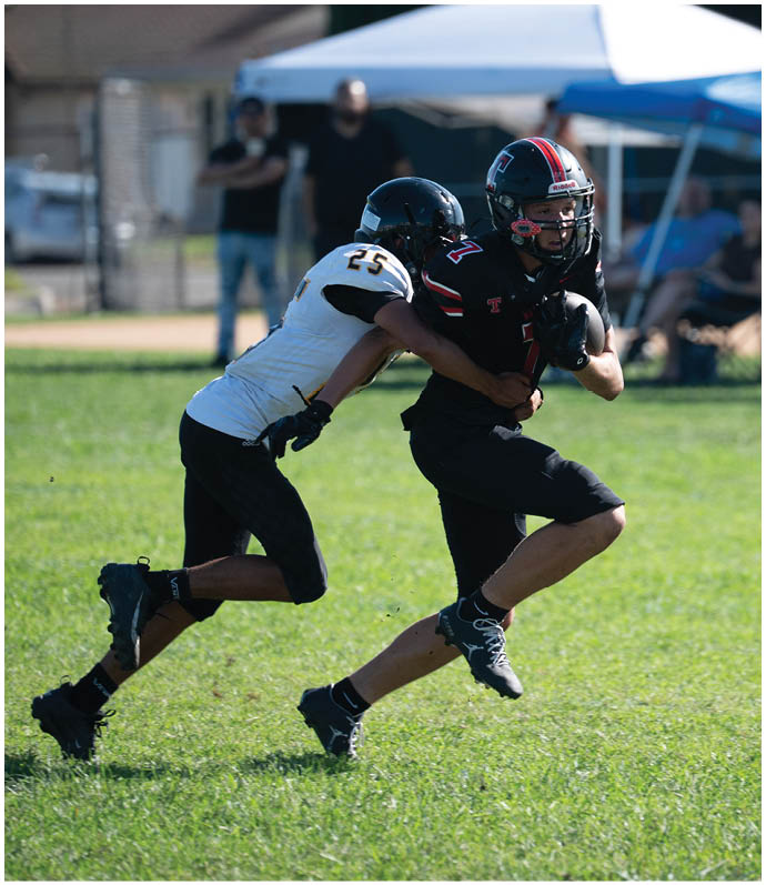 Three football players in blue and white uniforms running on a field. Description generated by AI
