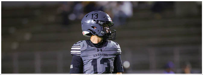 A football game is taking place on a field with players wearing blue and white uniforms. Description generated by AI