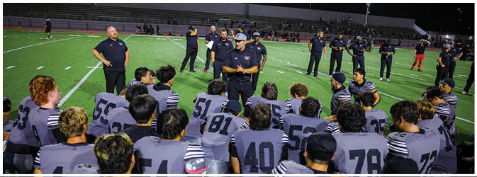 A football game is taking place on a field with players wearing blue and white uniforms. Description generated by AI
