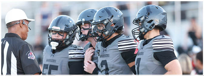 A football game is taking place on a field with players wearing blue and white uniforms. Description generated by AI