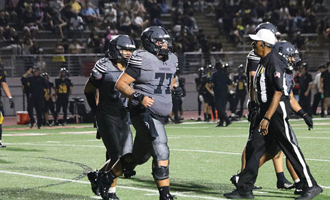 Two men wearing football uniforms are hugging each other on a field. AI generated content