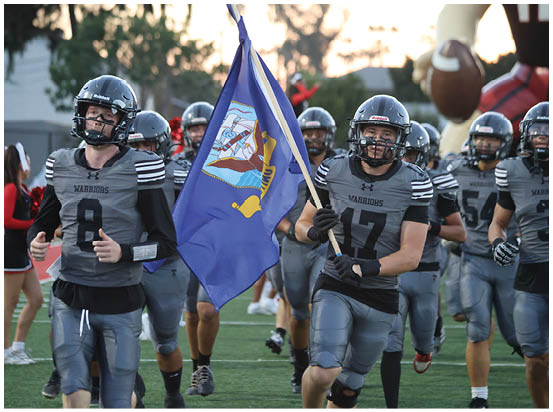 A football game is taking place on a field with players wearing blue and white uniforms. Description generated by AI