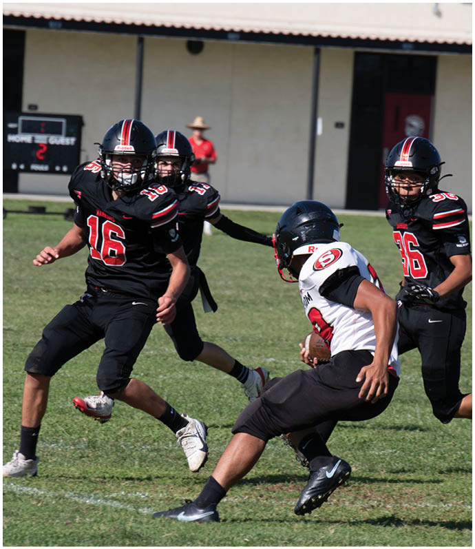 Three football players in blue and white uniforms running on a field. Description generated by AI