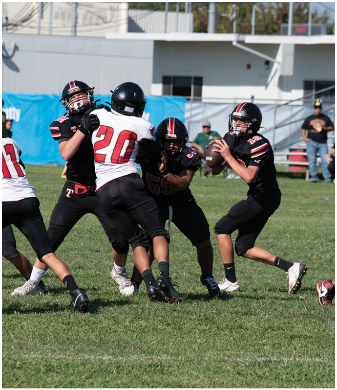 Three football players in blue and white uniforms running on a field. Description generated by AI
