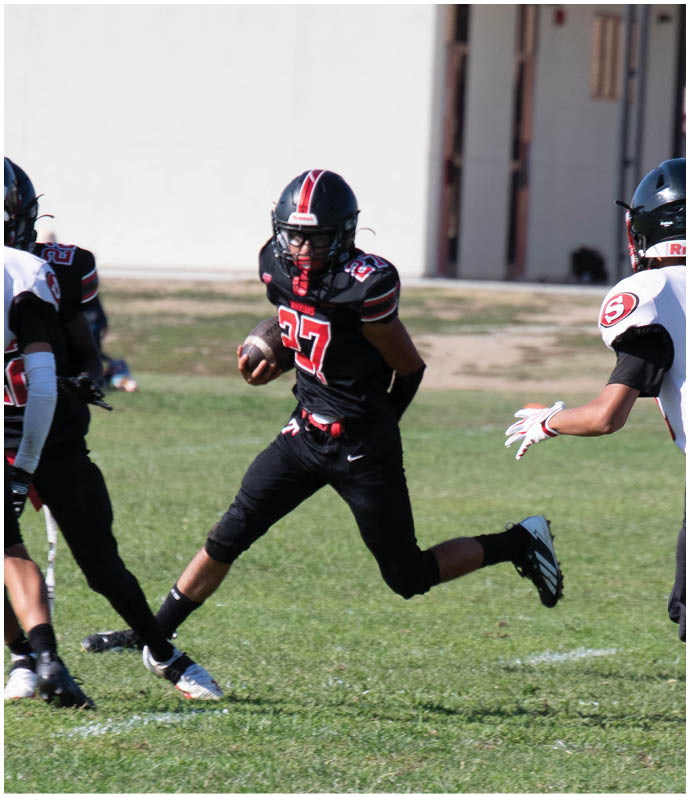 Three football players in blue and white uniforms running on a field. Description generated by AI