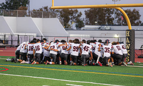 Two men wearing football uniforms are hugging each other on a field. AI generated content