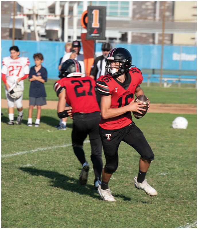 Three football players in blue and white uniforms running on a field. Description generated by AI