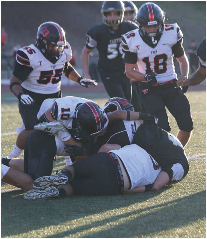 Three football players in blue and white uniforms running on a field. Description generated by AI