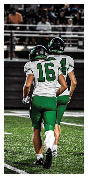A football player is kneeling on the field, wearing a green jersey and a helmet. AI generated content