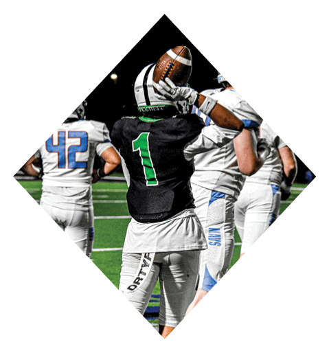 A football player wearing a black jersey with the number 10 sits on the ground with a football helmet on the ground next to him. AI generated content