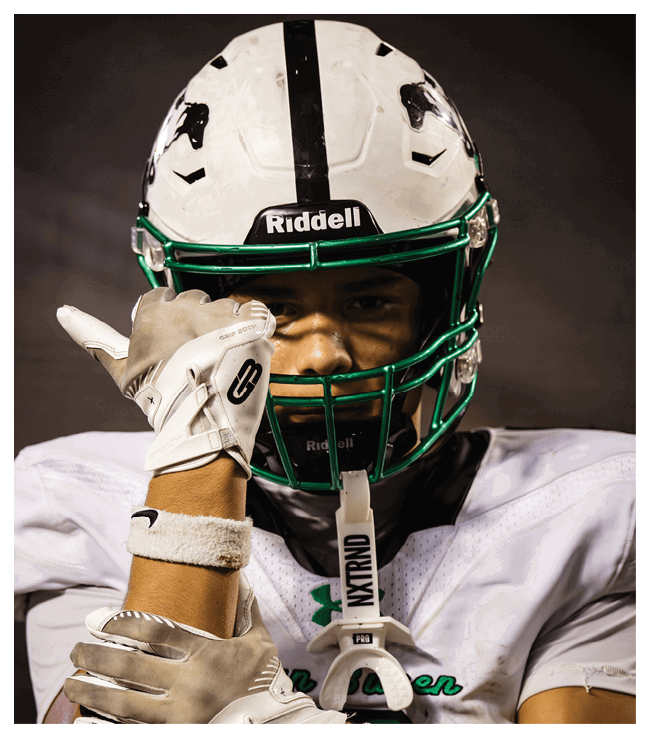 A football game is in progress with players on the field. One player is throwing a football while another player is trying to catch it. The players are wearing uniforms and are actively engaged in the game. AI generated content