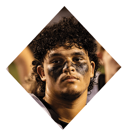 A football player wearing a black jersey with the number 3 kneels on the field. AI generated content