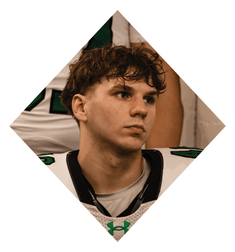 A football player wearing a black jersey with the number 10 sits on the ground with a football helmet on the ground next to him. AI generated content