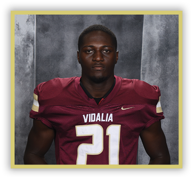 A person wearing a maroon football jersey with the number 21 and the word Vidalia stands against a gray textured background. Description generated by AI