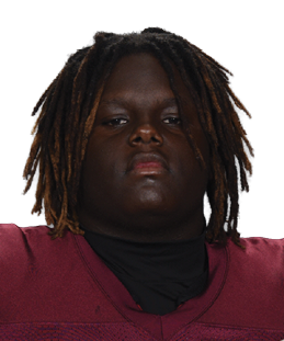 A person wearing a maroon football jersey with the number 54 and the word Vidalia is holding a football. Description generated by AI