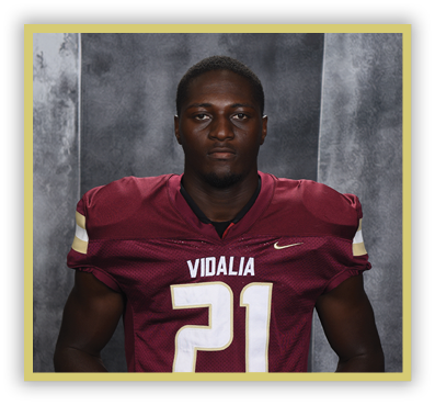 A person wearing a maroon football jersey with the number 21 and the word Vidalia stands against a gray textured background. Description generated by AI