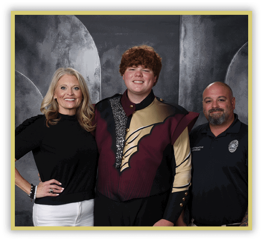 Three people stand together smiling, with one person in the center wearing a decorative maroon and gold uniform, flanked by two others in casual and professional attire against a dark backdrop. Description generated by AI