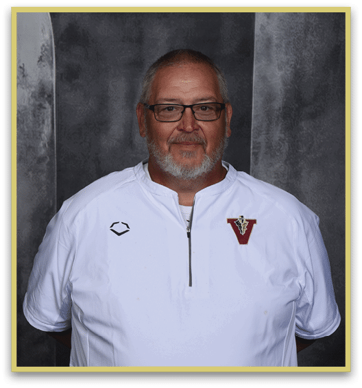 A person with short hair and glasses wearing a white zip-up shirt with a red and gold emblem stands against a dark gray mottled background. Description generated by AI