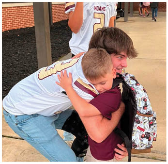Three people wearing sports jerseys are interacting outdoors near a building with large windows and brick walls. Description generated by AI