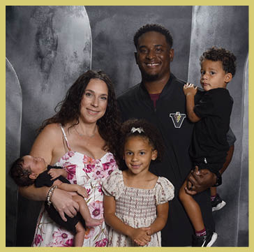 Five people wearing matching striped polo shirts and one person in a black shirt pose together against a dark, textured backdrop. Description generated by AI