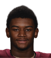A person wearing a maroon football jersey with the number 32 and the word Vidalia on it is holding a football and standing against a white background. Description generated by AI