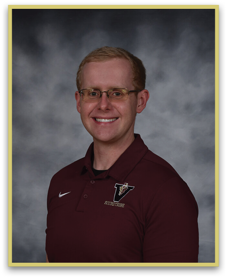 A person wearing glasses and a maroon polo shirt with a logo is smiling against a gray cloudy background. Description generated by AI