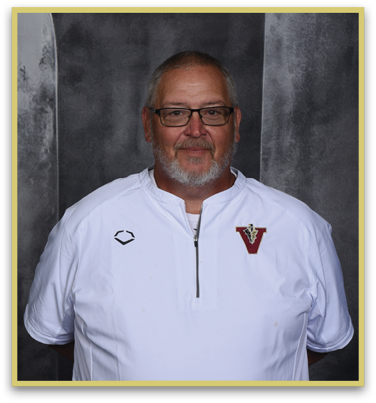 A person with short hair and glasses wearing a white zip-up shirt with a red and gold emblem stands against a dark gray mottled background. Description generated by AI