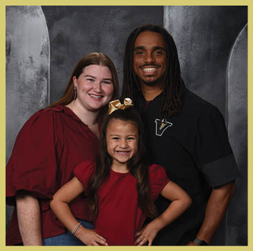 Five people wearing matching striped polo shirts and one person in a black shirt pose together against a dark, textured backdrop. Description generated by AI