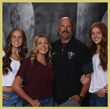 Five people wearing matching striped polo shirts and one person in a black shirt pose together against a dark, textured backdrop. Description generated by AI