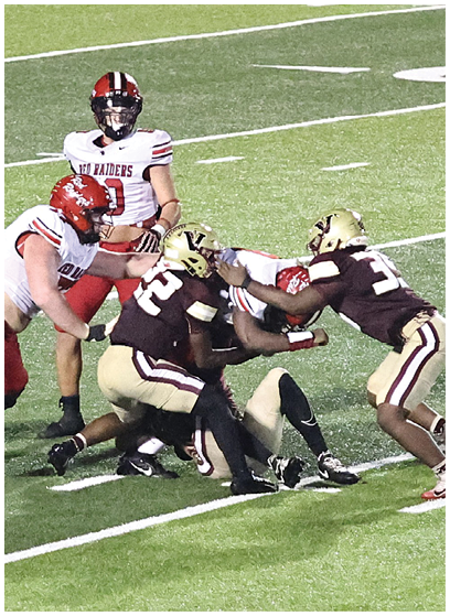 Several people wearing football uniforms are engaged in a play on a grassy field with one person on the ground and others around them. Description generated by AI