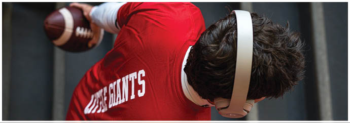 A group of people wearing red sports jerseys with “WABASH" written on them are gathered closely together, with one person in a white shirt facing them. Description generated by AI