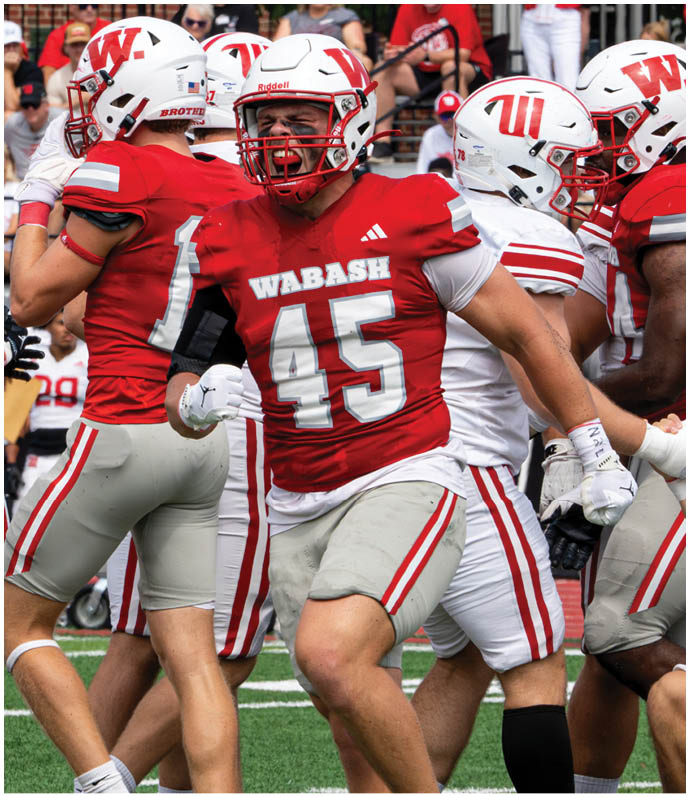 A person in a red football uniform tackles another person in a white football uniform who is holding a football on a green field during a game. Description generated by AI